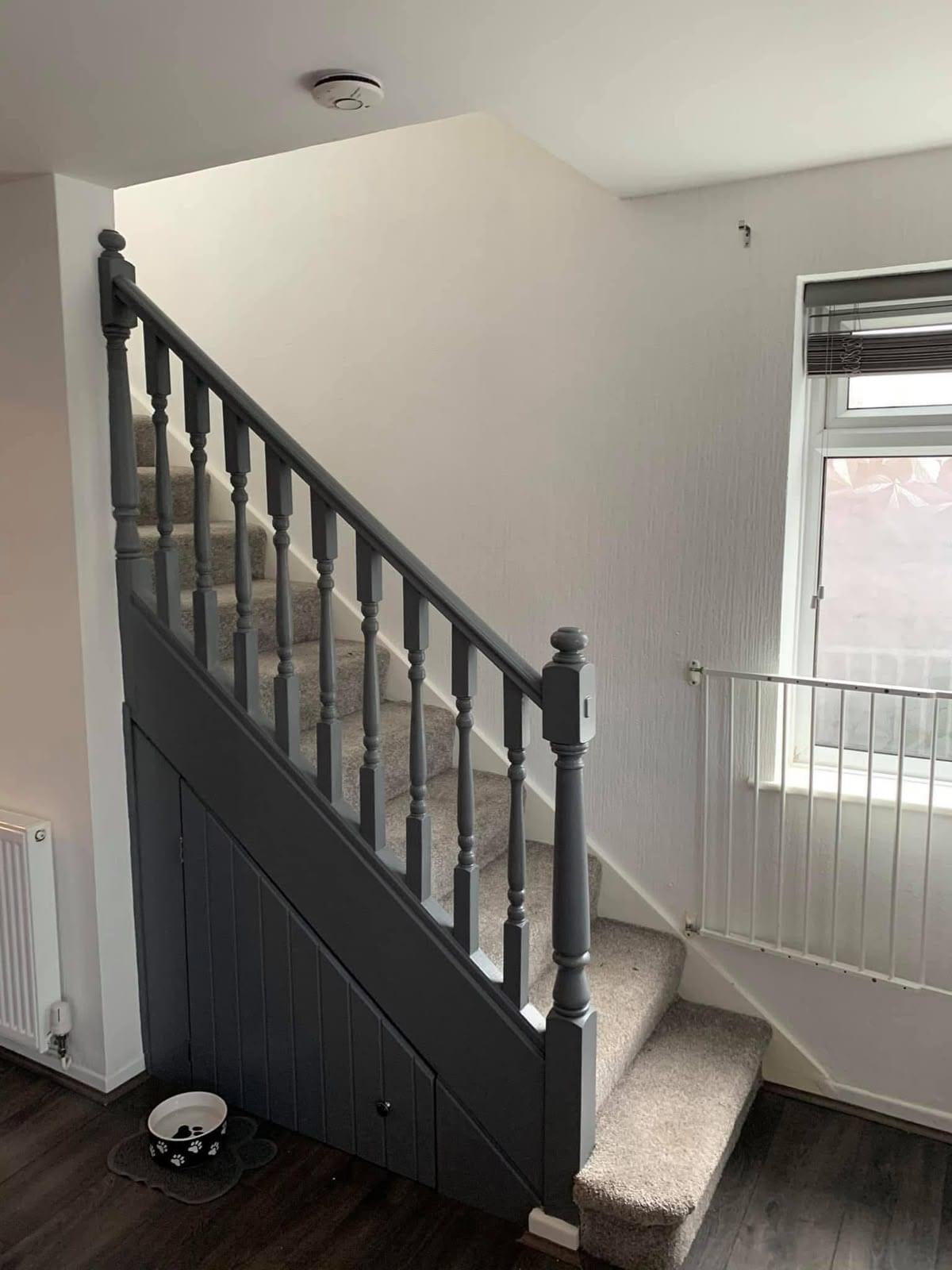 Staircase and understairs cupboards finished in a mid grey, with grey carpet